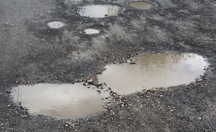 Puddles standing in a potholed parking lot